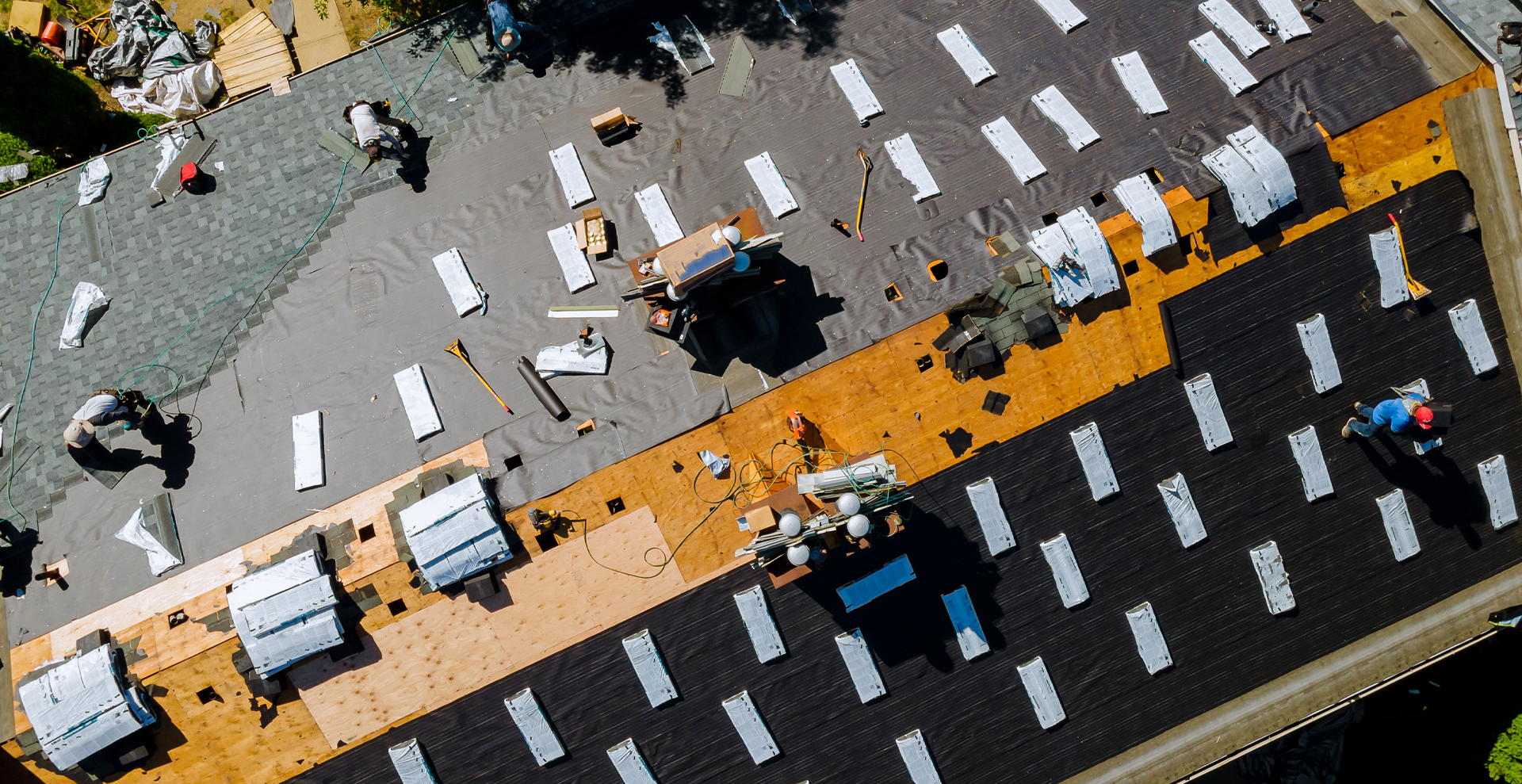 Aerial view of roof with workers installing new shingles. Background element for decorative purposes only.